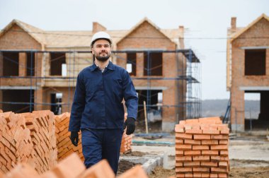 Üniformalı inşaat işçisi ve güvenlik ekipmanı inşaatında çalışıyor.