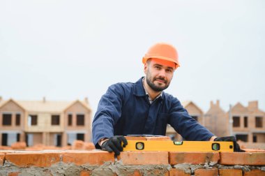 Üniformalı inşaat işçisi ve güvenlik ekipmanı inşaatında çalışıyor.