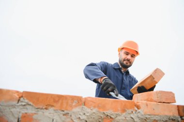 Üniformalı inşaat işçisi ve güvenlik ekipmanı inşaatında çalışıyor.