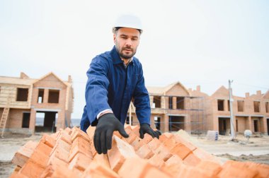 Üniformalı inşaat işçisi ve güvenlik ekipmanı inşaatında çalışıyor.