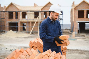 Üniformalı inşaat işçisi ve güvenlik ekipmanı inşaatında çalışıyor.