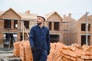İnşaat alanındaki bir inşaatçının portresi. Tuğla evler inşa ediliyor.