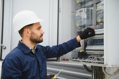 Bir erkek elektrikçi santralde çalışıyor..