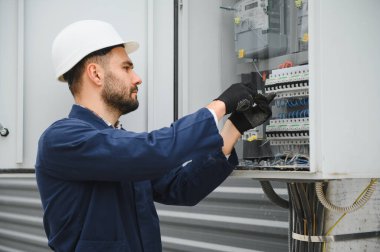 Bir erkek elektrikçi santralde çalışıyor..