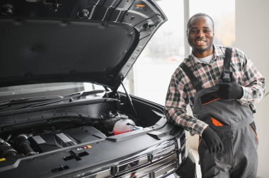 Afrikalı bir adam araba tamirhanesinde duruyor..