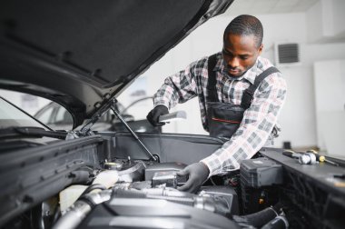 Afro-Amerikalı bir tamirci atölyesinde elinde aletlerle güvenle poz veriyor..