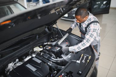 Afro-Amerikalı bir tamirci atölyesinde elinde aletlerle güvenle poz veriyor..
