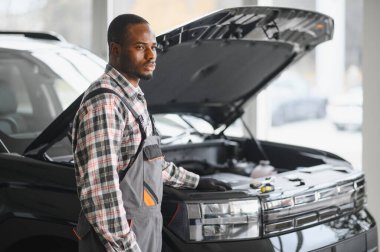 Afro-Amerikalı bir tamirci atölyesinde elinde aletlerle güvenle poz veriyor..