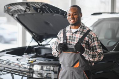 Afro-Amerikalı bir tamirci atölyesinde elinde aletlerle güvenle poz veriyor..
