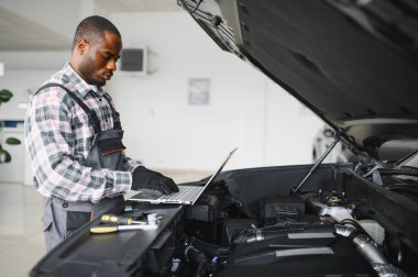 Servis istasyonunda çalışan yetenekli bir teknisyen, araba tamir ediyor..