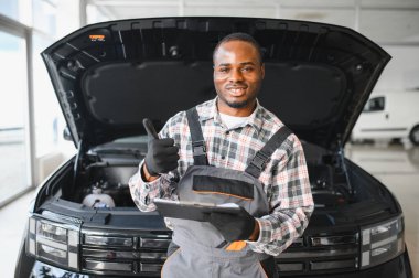 Afrikalı bir adam araba tamirhanesinde duruyor..
