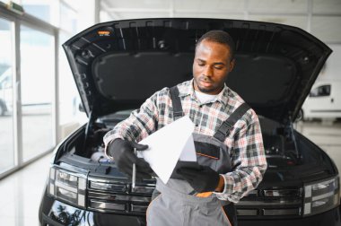 Araba servisi, onarım, bakım konsepti, atölyedeki panoya yazı yazan oto tamircisi, tamir makinesi için kontrol listesi hazırlayan teknisyen garajda bir araba, afiş..