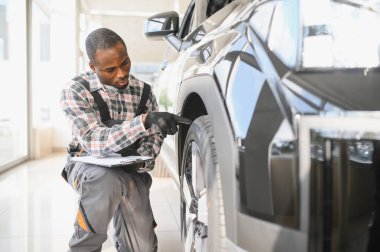 Araba servisi, onarım, bakım konsepti, atölyedeki panoya yazı yazan oto tamircisi, tamir makinesi için kontrol listesi hazırlayan teknisyen garajda bir araba, afiş..