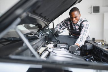 Servis istasyonunda çalışan yetenekli bir teknisyen, araba tamir ediyor..