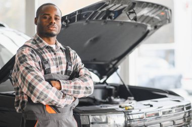 African man standing in a car repair shop. clipart