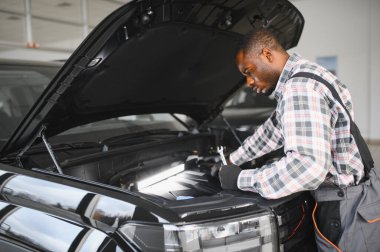 Servis istasyonunda çalışan yetenekli bir teknisyen, araba tamir ediyor..