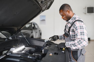 Araba servisindeki gülümseyen tamircinin portresi hasarlı araç için tablet kullanarak yeni parçalar sipariş ediyor. Bozuk arabalardaki eski parçaların yerine yenilerini arayan Afrikalı Amerikalı bir tamirci.