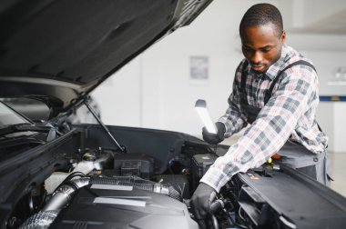 Afro-Amerikalı bir tamirci atölyesinde elinde aletlerle güvenle poz veriyor..