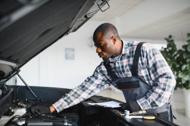 Araba servisi, onarım, bakım konsepti, atölyedeki panoya yazı yazan oto tamircisi, tamir makinesi için kontrol listesi hazırlayan teknisyen garajda bir araba, afiş..