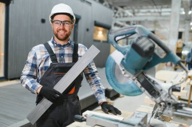 Bir işçi kereste fabrikasını ahşap işlemek için kullanır. Modern modüler evlerin inşası