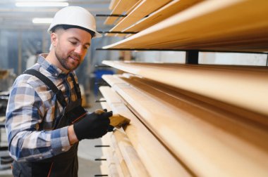 Bir işçi ahşap bir ev inşa etmek için tahtaları cilalar.