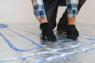 Boru tesisatçısı zemin altı ısıtması monte etti. Isıtma sistemi ve yer altı ısıtma sistemi. Merkezi ısıtma.