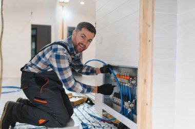 Boru tesisatçısı zemin altı ısıtması monte etti. Isıtma sistemi ve yer altı ısıtma sistemi. Merkezi ısıtma.