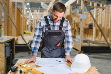 Modüler evlerin yapımı. İnşaat alanındaki bir mimar planlara bakar..