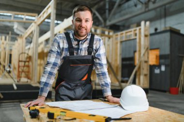 Modüler evlerin yapımı. İnşaat alanındaki bir mimar planlara bakar..