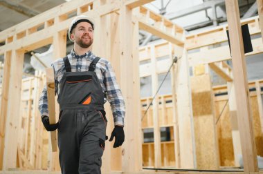 Modüler evlerin yapımı. Üniformalı ve inşaat alanında çalışan erkek inşaat işçisi..