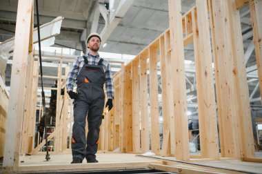 Modüler evlerin yapımı. Üniformalı ve inşaat alanında çalışan erkek inşaat işçisi..