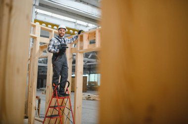 Modüler evlerin yapımı. Üniformalı ve inşaat alanında çalışan erkek inşaat işçisi..