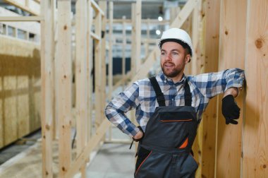 Modüler evlerin yapımı. Üniformalı ve inşaat alanında çalışan erkek inşaat işçisi..