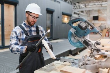 Bir işçi kereste fabrikasını ahşap işlemek için kullanır. Modern modüler evlerin inşası