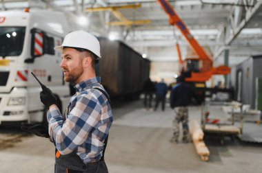 Foreman telsiz kullanarak prefabrik modüler bir evi kamyondan kamyona yüklüyor..