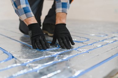 Boru tesisatçısı zemin altı ısıtması monte etti. Isıtma sistemi ve yer altı ısıtma sistemi. Merkezi ısıtma.