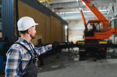 Foreman telsiz kullanarak prefabrik modüler bir evi kamyondan kamyona yüklüyor..