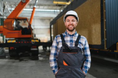 Foreman telsiz kullanarak prefabrik modüler bir evi kamyondan kamyona yüklüyor..