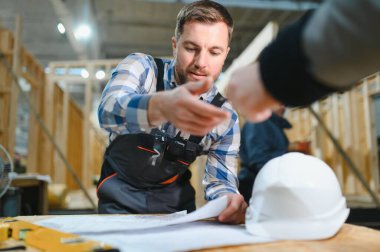 Modüler evlerin yapımı. İnşaat alanındaki bir mimar planlara bakar..