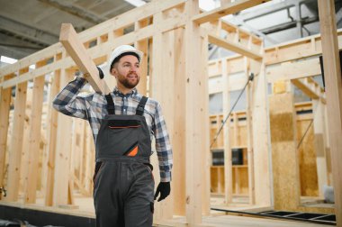 Kereste deposunda çapraz kollarla gülümseyen bir marangozun portresi, modüler yapı endüstrisinde uzmanlık gösteriyor..