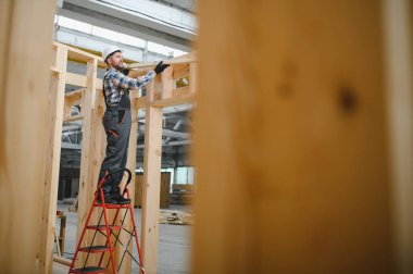 Modüler evlerin yapımı. Üniformalı ve inşaat alanında çalışan erkek inşaat işçisi..