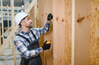 Modüler evlerin yapımı. Üniformalı ve inşaat alanında çalışan erkek inşaat işçisi..