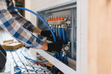 Boru tesisatçısı zemin altı ısıtması monte etti. Isıtma sistemi ve yer altı ısıtma sistemi. Merkezi ısıtma.