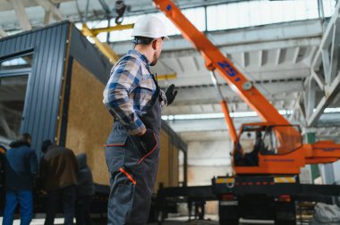Bir işçi modüler evi kamyona yükleme işlemini kontrol eder. Ulaşım ve teslimat kavramı.