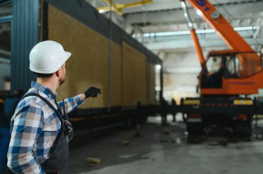 Bir işçi modüler evi kamyona yükleme işlemini kontrol eder. Ulaşım ve teslimat kavramı.