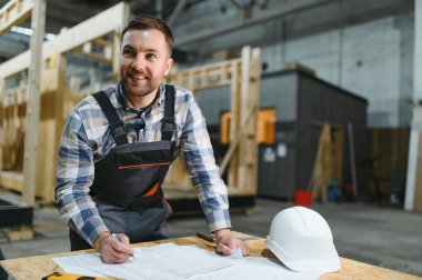 Modern modüler evlerin inşaatı. Bir mimar bina planlarıyla çalışır..