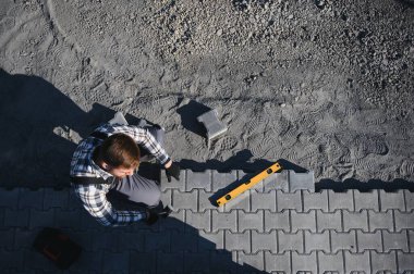 Eldivenli ellerle kum temel üzerine yerleştirerek bir kaldırım tuğla döşeme Oluşturucu.