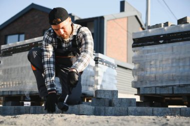 Eldivenli ellerle kum temel üzerine yerleştirerek bir kaldırım tuğla döşeme Oluşturucu.