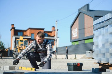 Eldivenlerin ustası katman katman taş döşüyordu. Profesyonel kaldırım işçisi tarafından kaldırım taşı döşenmiş. Kum temeli üzerine ev avlusunda gri beton döşeme döşeme döşeme döşeme.