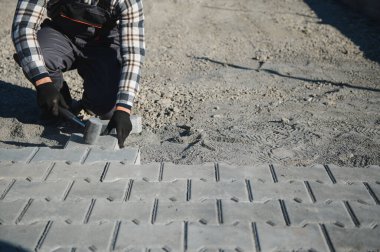Eldivenli ellerle kum temel üzerine yerleştirerek bir kaldırım tuğla döşeme Oluşturucu.